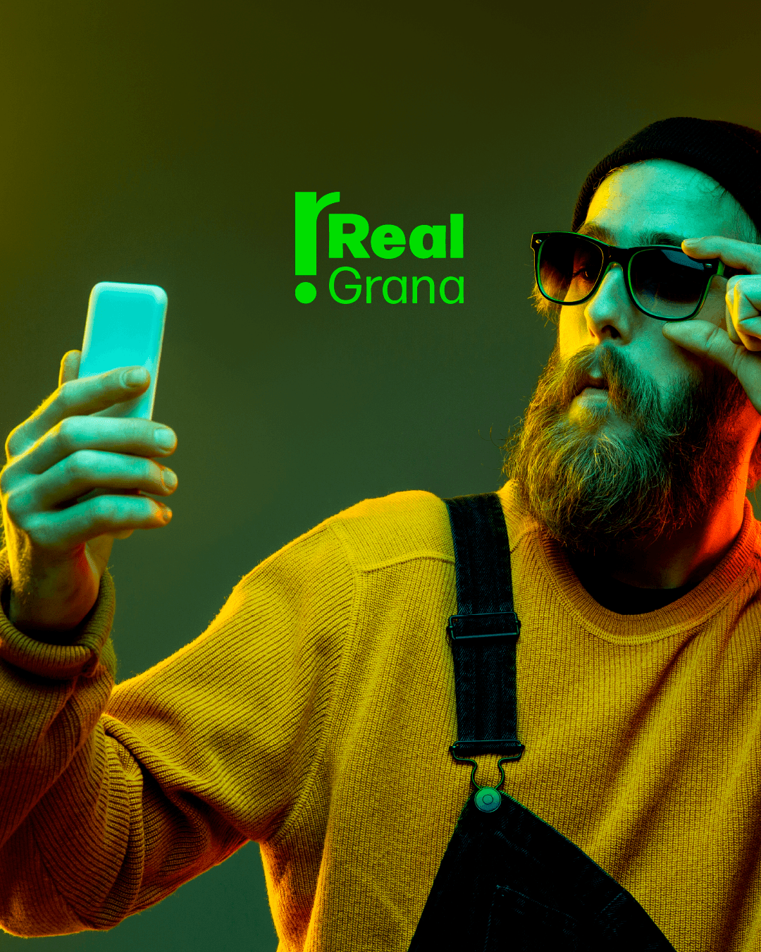 Homem com celular e óculos, tirando foto para a Real Grana